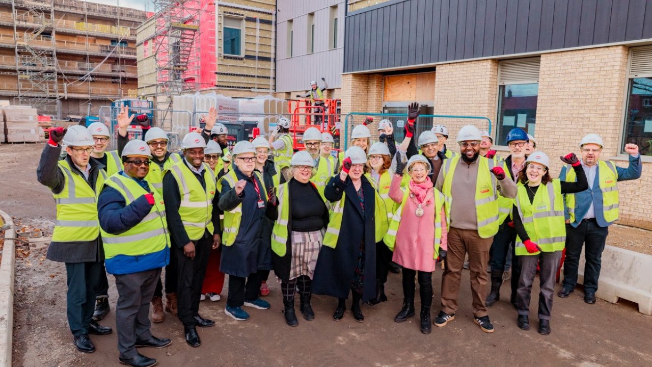 Project team in hard hats and high vis infront of new school building