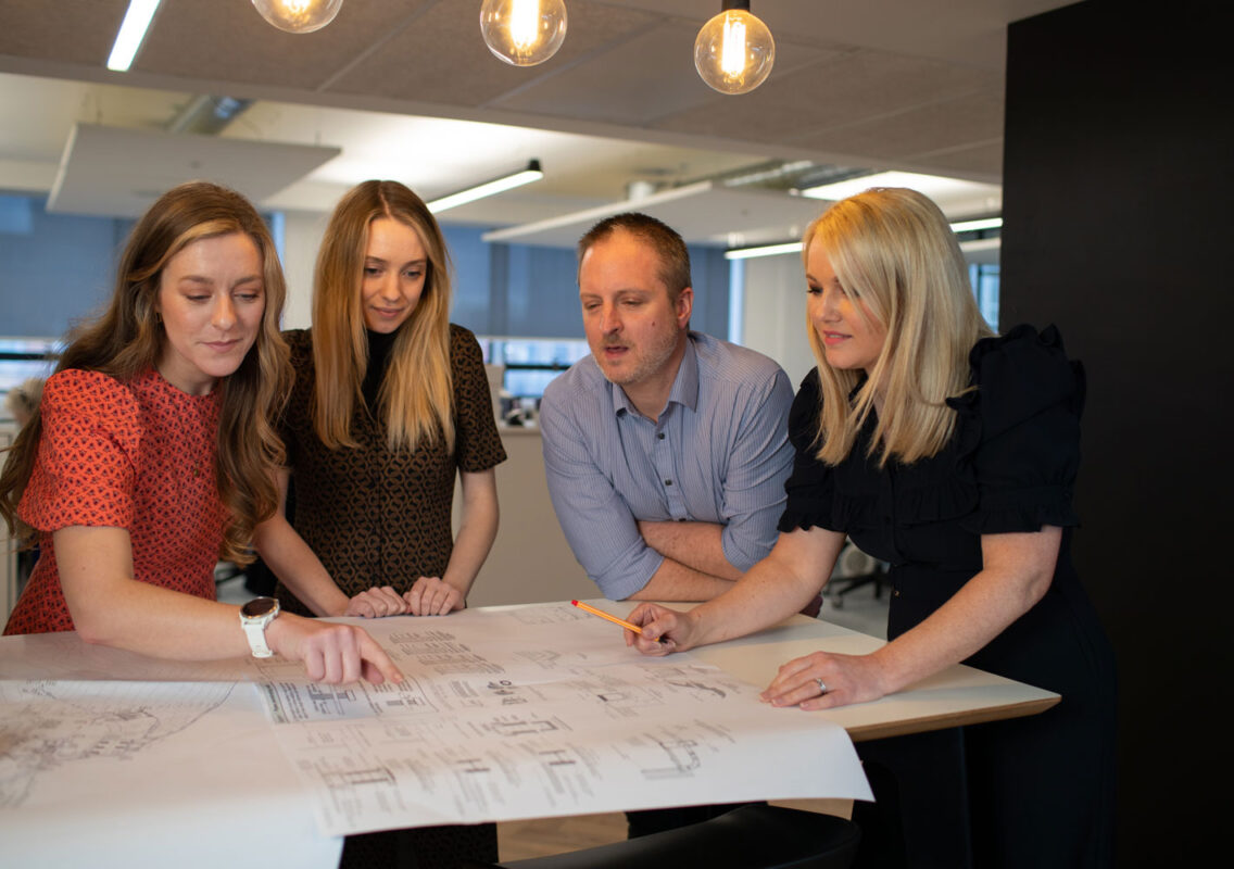 People leaning over a drawing in an office