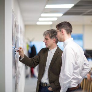 Two people drawing on a whiteboard