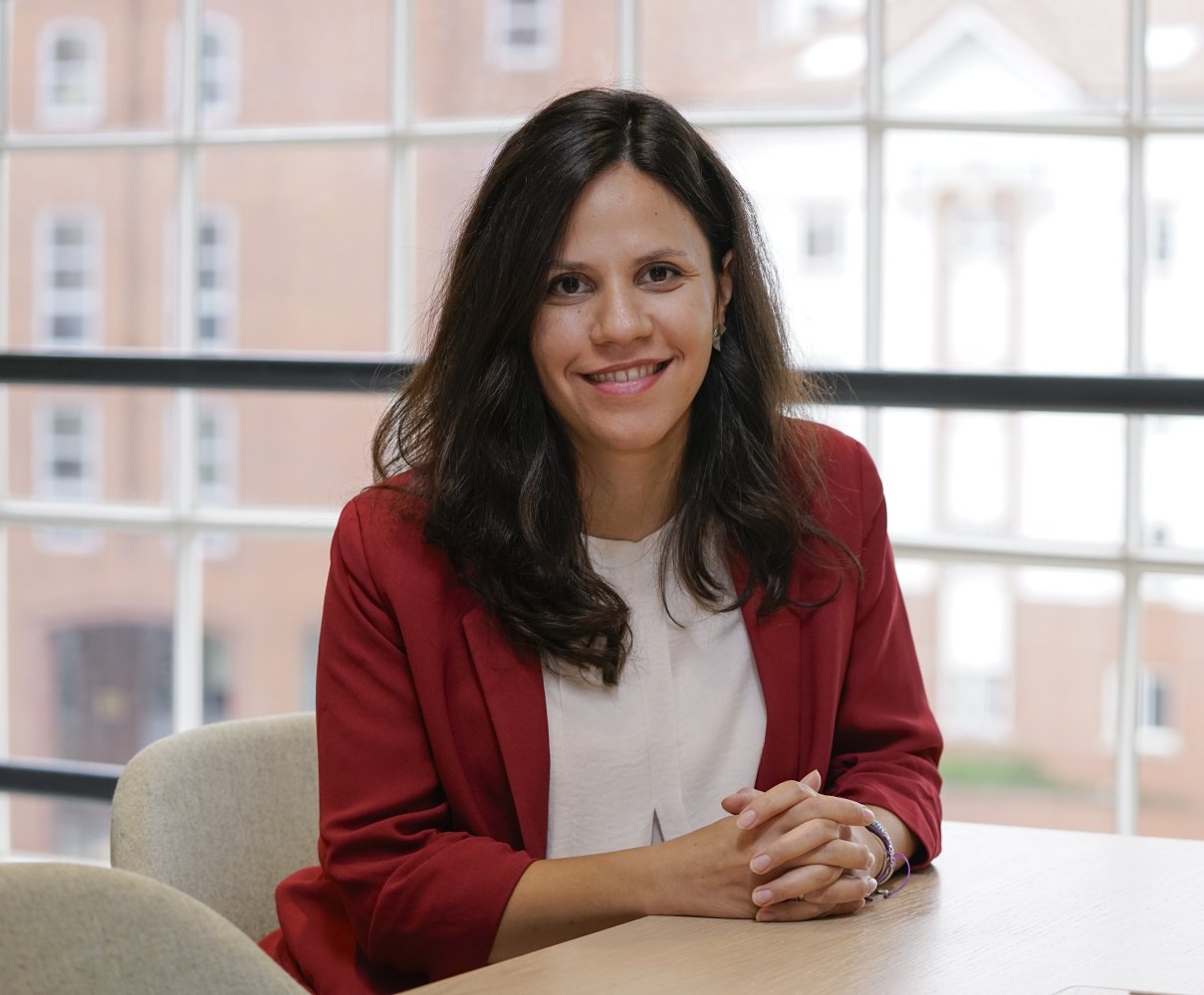 Olia Kyritsi in the office in a white shirt and red blazer