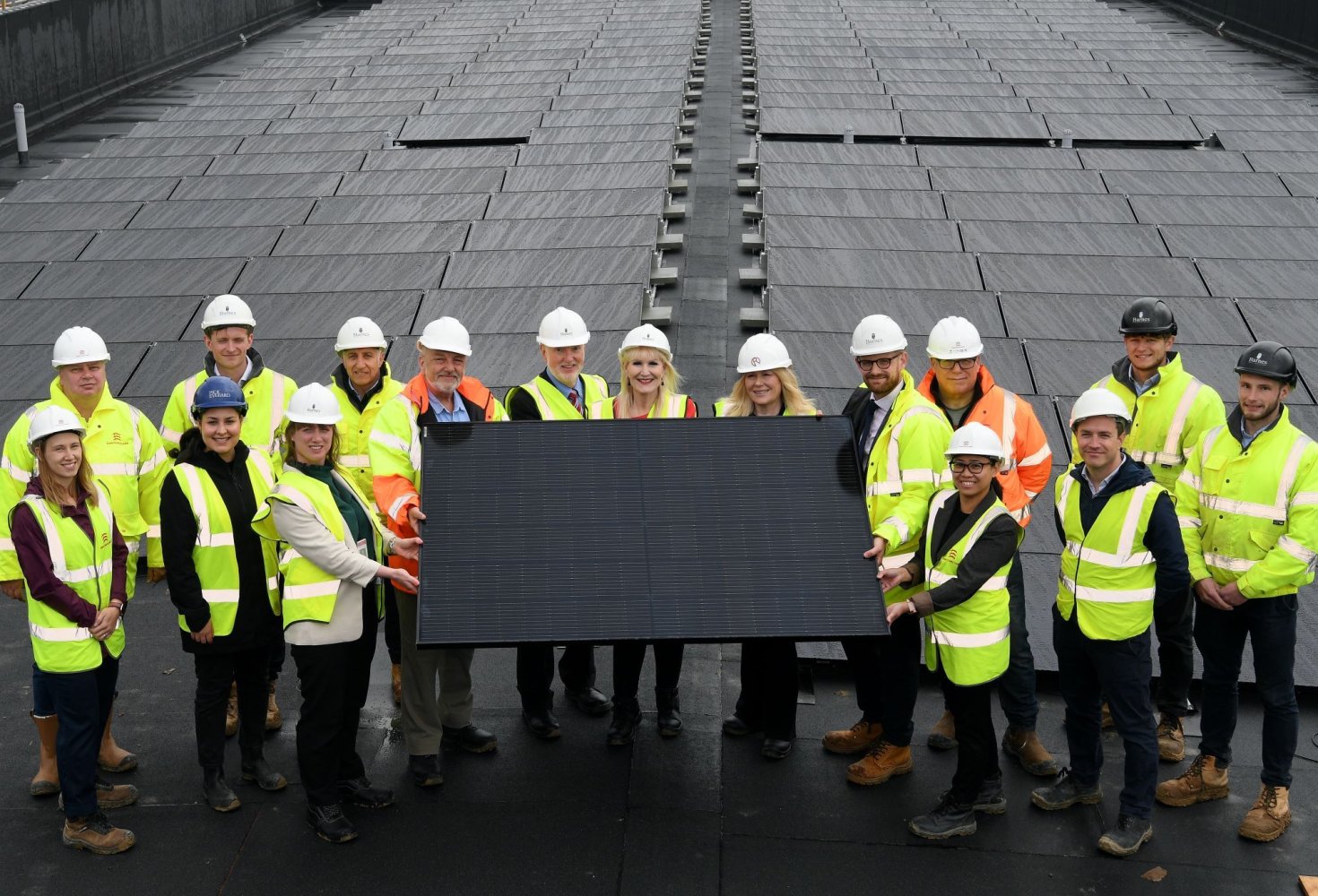Group gathered around in a semicircle holding solar panel