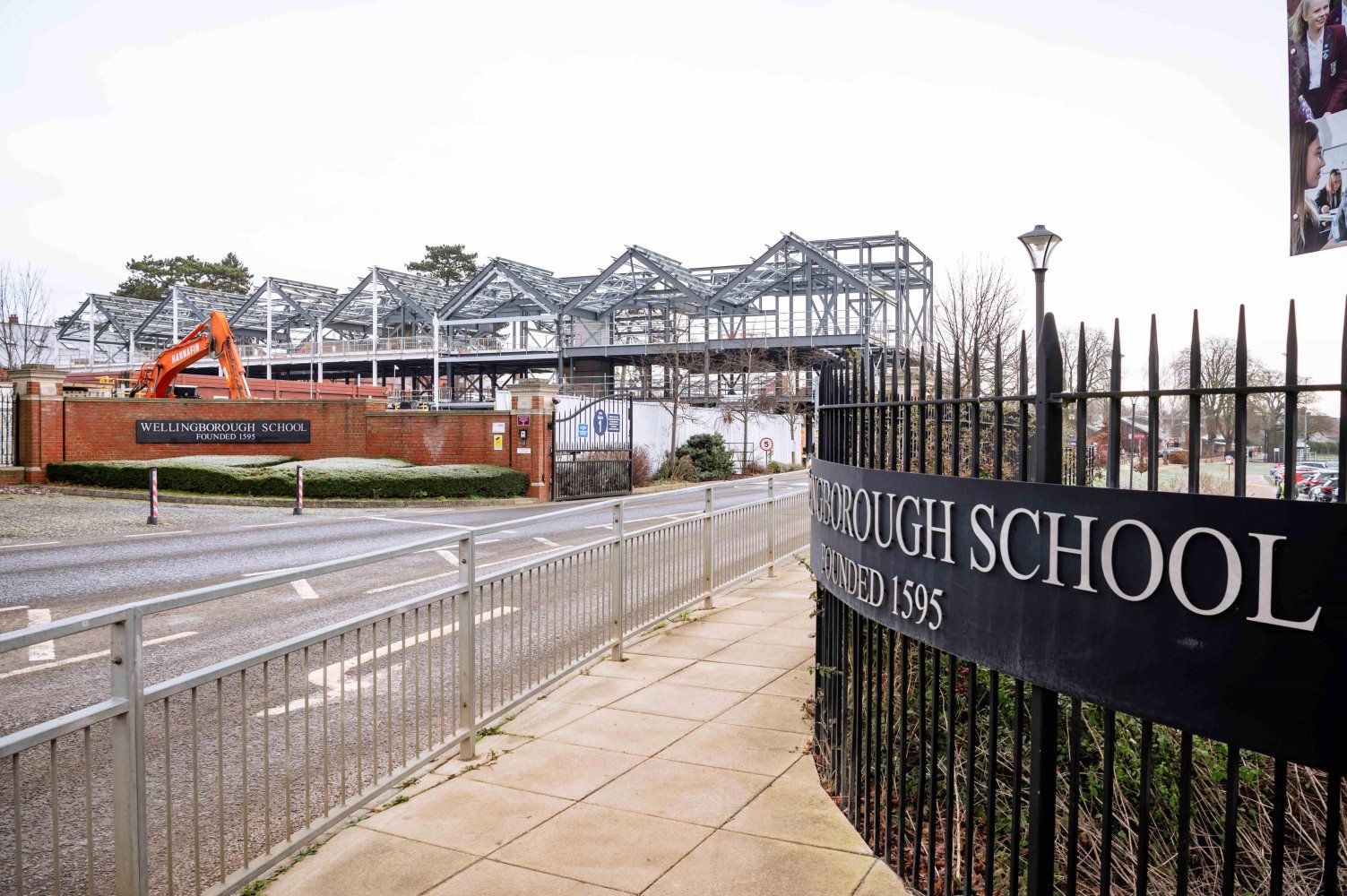 Photo taken at the gates of the school with steel beams of the new school in the background