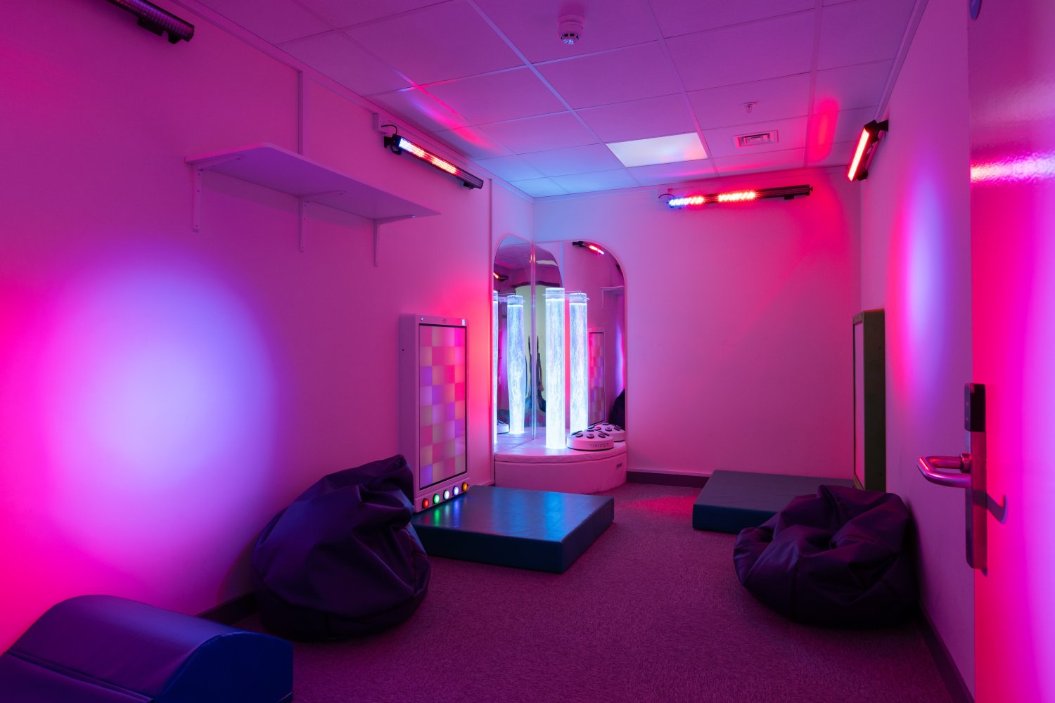 Sensory room with purple lights and a bubble tube
