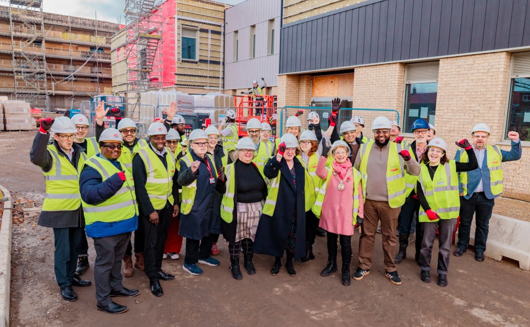 Project team in hard hats and high vis infront of new school building
