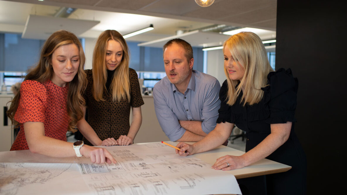 People leaning over a drawing in an office