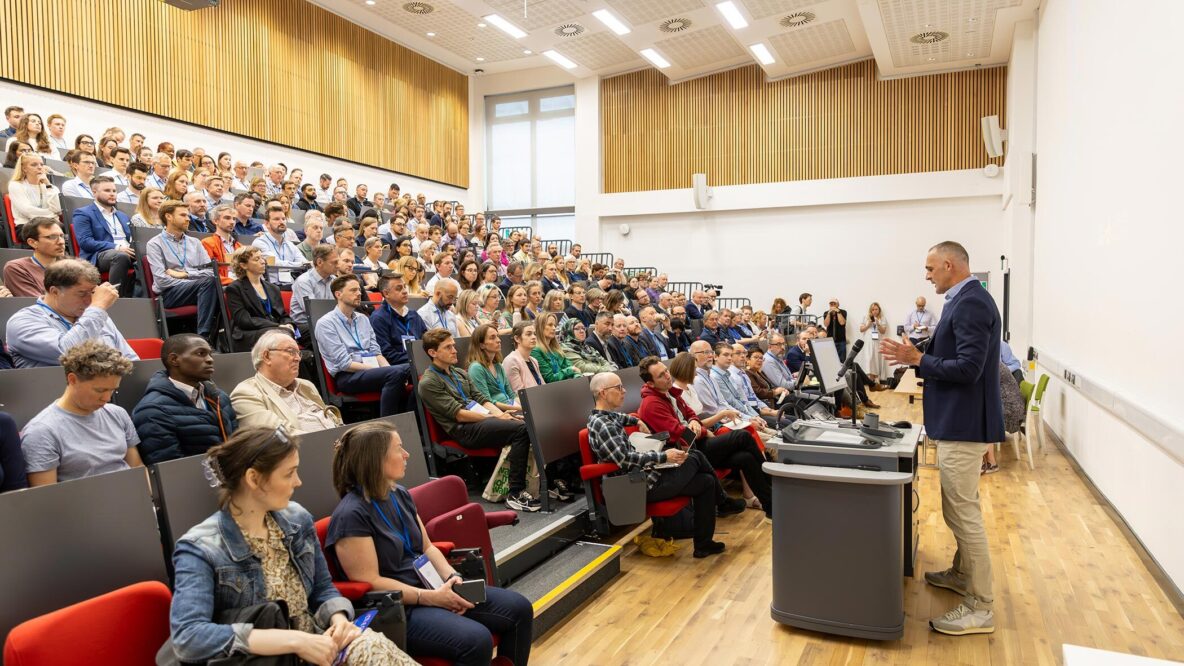 Speaker in front of a full lecture theatre