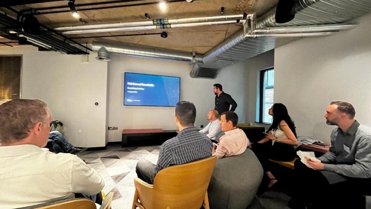 Professionals sit around a TV screen presentation in a modern office