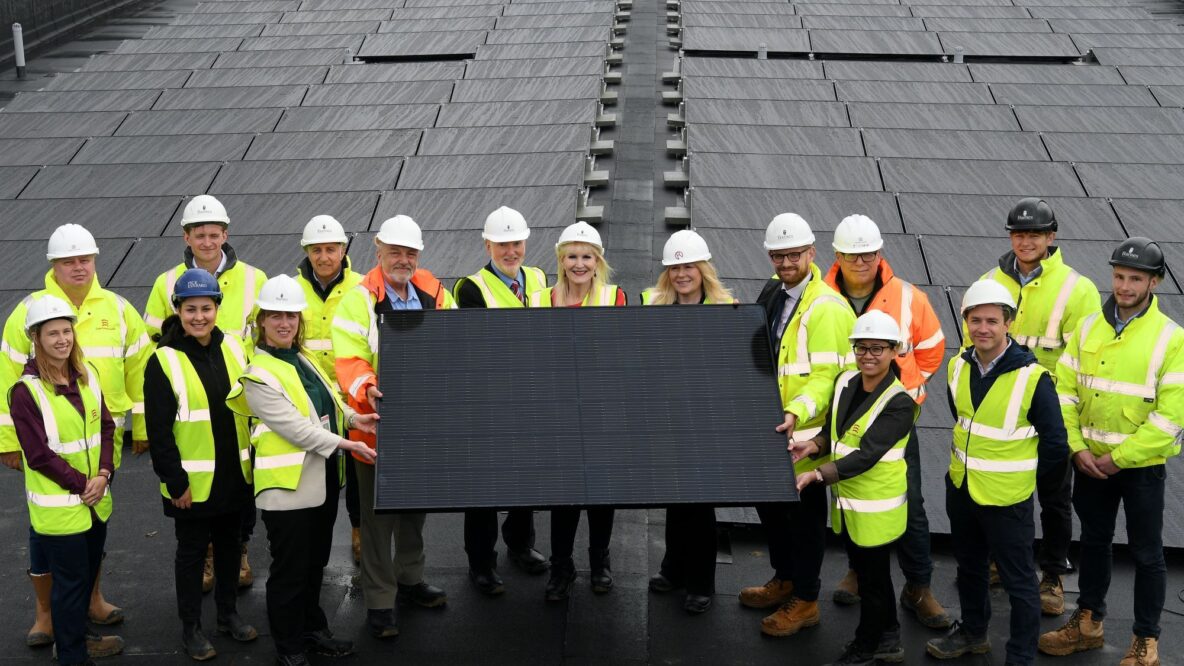 Group gathered around in a semicircle holding solar panel