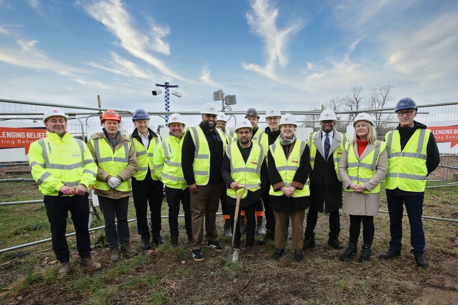 Group of people stood together wearing hardhats and high vis vests smiling