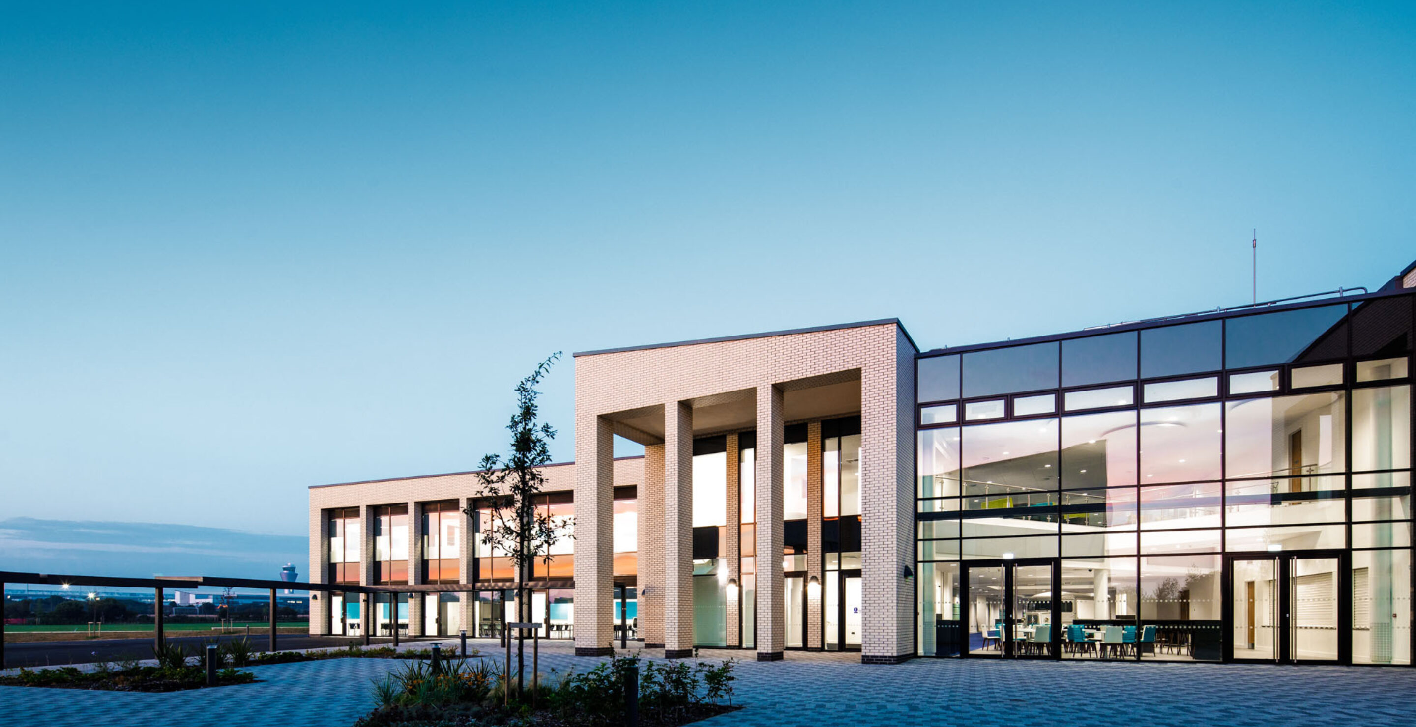 A photo of the outside of the school with blue skies and clean gardens