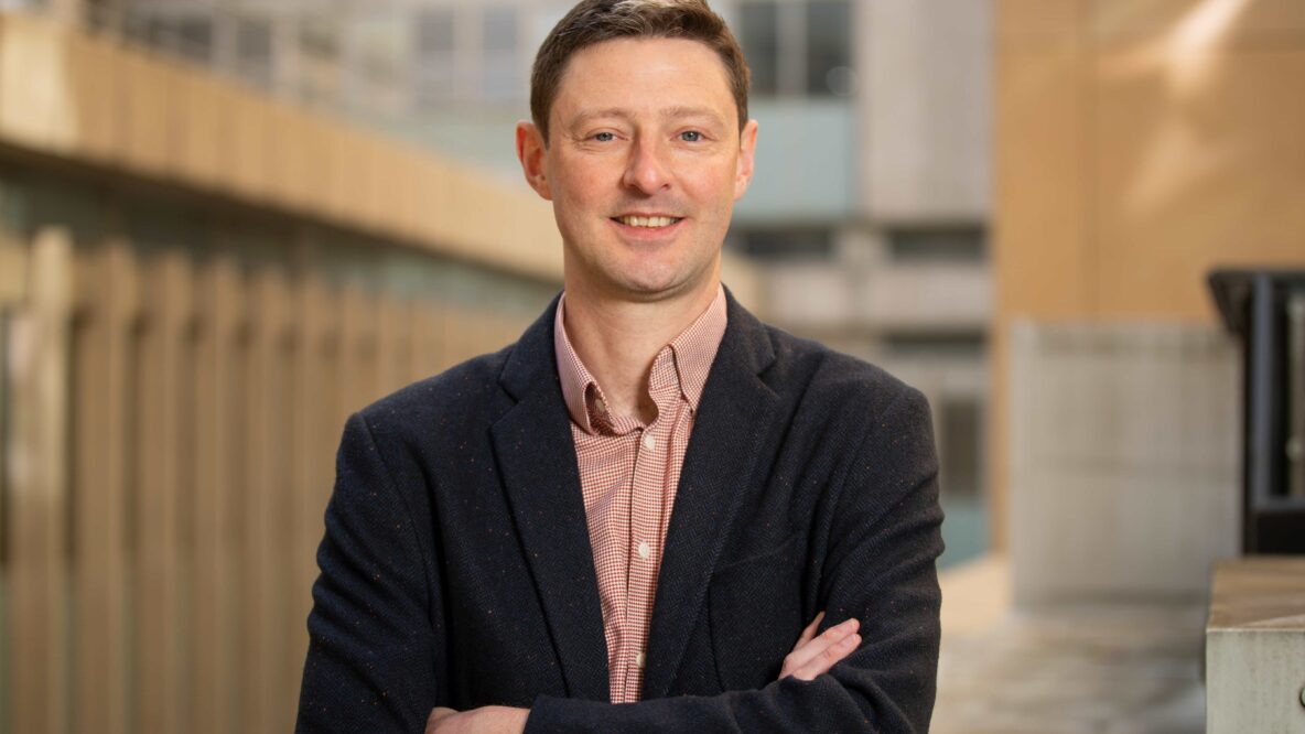 Tom Smith, associate director of ecology standing up with his arms folded