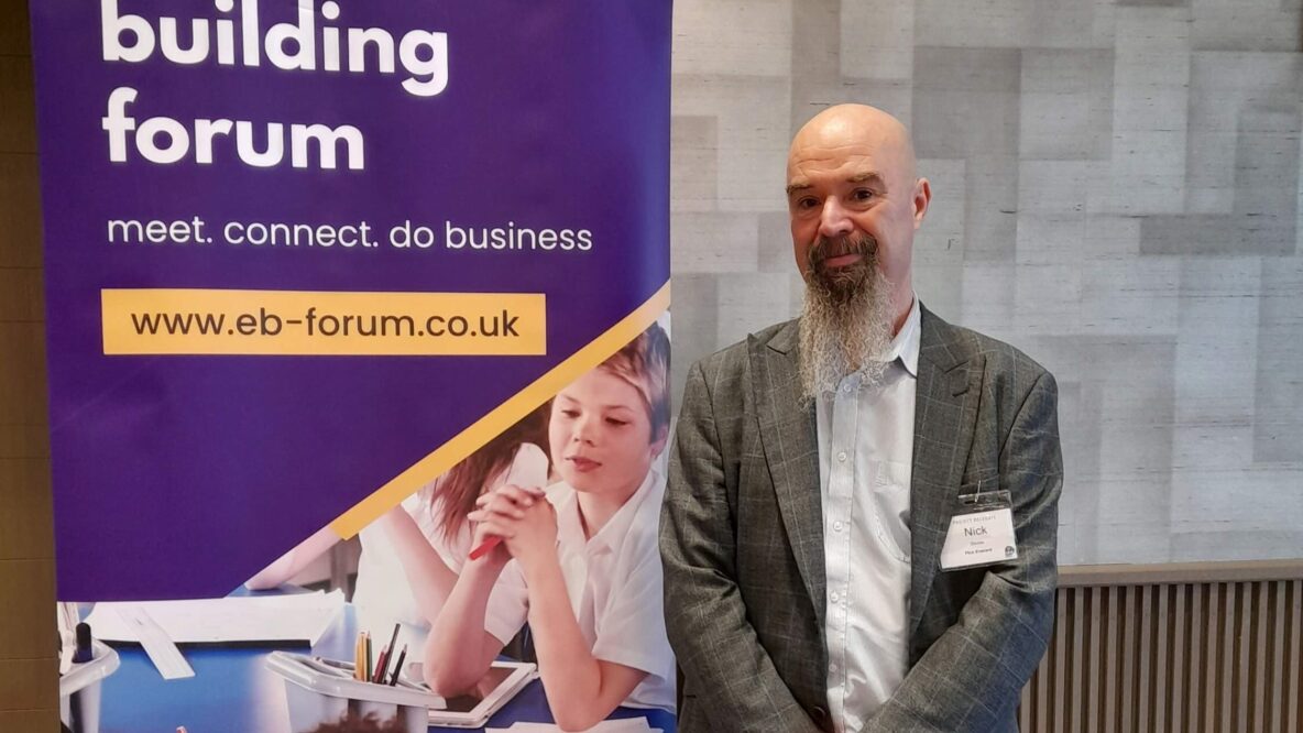 Nick stood next to a pop up banner that reads Education Building Forum