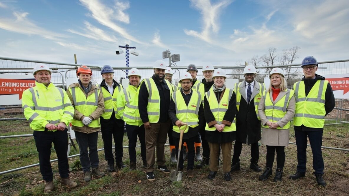 Group of people stood together wearing hardhats and high vis vests smiling